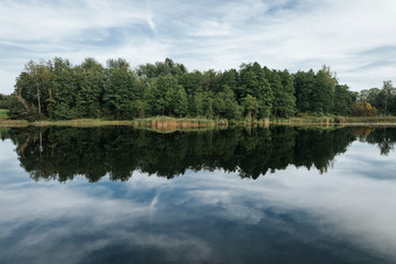 Fototapeta na wymiar Forest reflection in blue lake