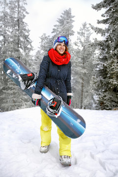 Woman holding snowboard in mountain