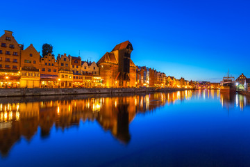 Obraz premium Gdansk at night with historic port crane reflected in Motlawa river, Poland