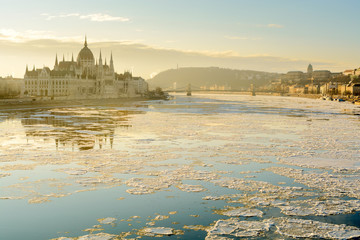Winter view of Parliament building and Chain bridge across Danube river covered with scattered ice