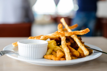 Delicious fried potato, croutons and sauce in a white plate in a restaurant, shallow dof