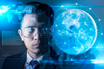 The abstract image of business man using a vr glasses overlay with earth hologram image and element of this image furnished by Nasa. the concept of communication, internet of things and future life.