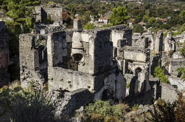 Turkey, the ghost town of Kayakoy, on the slope of the mountain abandoned houses, close-up depicts the walls of the destroyed houses, in the foreground the destroyed Greek hearth