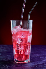 fizzy drink with ice in glass on dark background