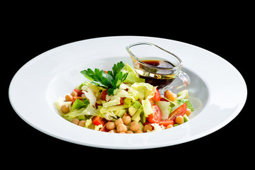 Vegetarian salad with tomato, avocado, salad and soy sauce in a white plate isolated on black background. Top view, flat lay