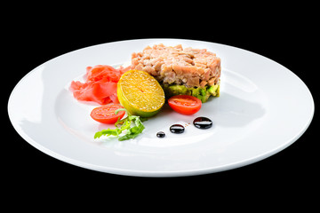 Tasty Tuna Tartare with lime, ginger and avocado in a white plate isolated on black background, close-up