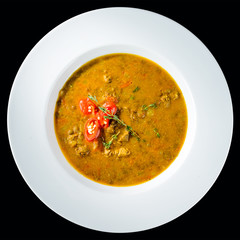 Tasty chili soup with basil in a white plate isolated on dark background. Traditional Italian cuisine