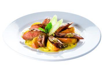Juicy roasted appetizing golden crispy duck fillet served with baked apples in a white plate