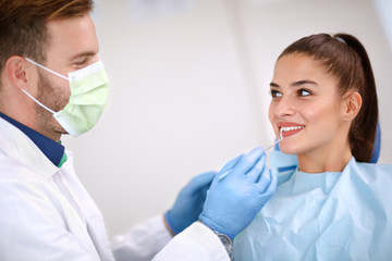 Dentist examine woman’s teeth with mirror