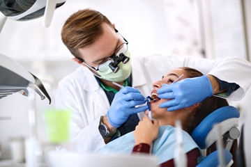 Dentist make checkup of female’s teeth