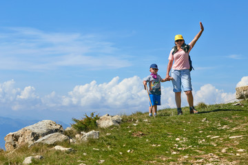 Mount Baldo, Italy - August 15, 2017: Happy mother with her son walking tourists on the mountain.