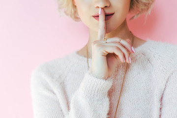 cropped shot of young woman gesturing for silence isolated on pink