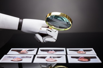 Robot Looking At Candidate Photograph With Magnifying Glass