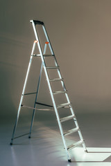 open metallic stepladder in studio on grey