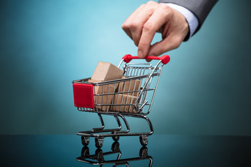 Businessperson Holding Shopping Cart With Cardboard Boxes