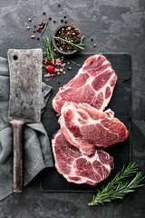 Fresh steaks from Raw pork meat on dark stone background, Top view