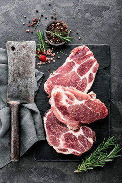 Fresh steaks from Raw pork meat on dark stone background, Top view