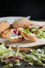 sandwiches with fresh herbs, sour cream and cheese and bread on a dark background