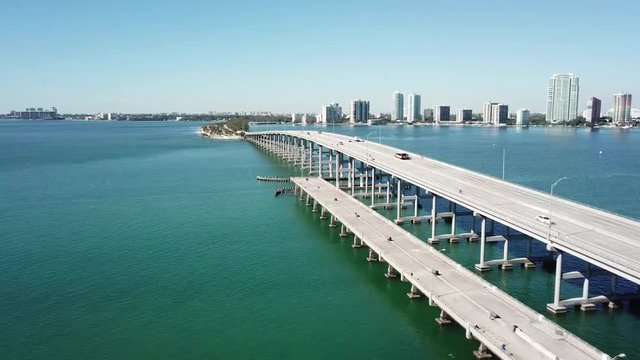 Amazing 4k aerial drone panorama shot of highway road on huge steel modern bridge across turquoise blue ocean cityscape