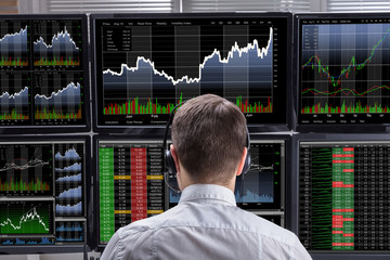 Stock Market Broker Analyzing Graphs On Computer Screens