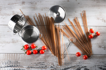 Spaghetti mit Tomaten und Töpfen auf  rustikalem Holz Tisch, top view