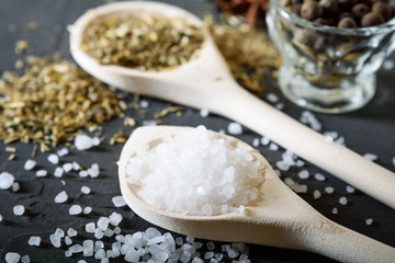  Wooden spoon with Italian seasoning - dried oregano with thyme, basil and vegetables .Oregano in a wooden spoon on a rocky concrete dark black background with a place for text Top view. A wooden spoo