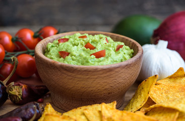 Guacamole in Wooden Bowl with Tortilla Chips and Ingredients