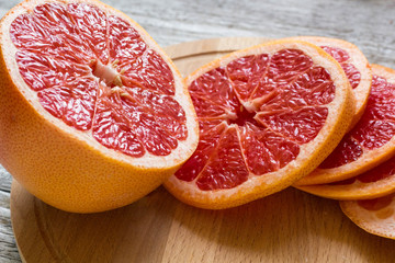 Sliced pieces of grapefruit with a knife. On white wooden background