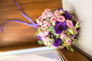 Wedding bouquet with purple and pink roses, violet flowers lying on a wooden windowsill 