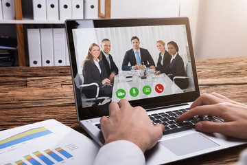 Businessperson Video Conferencing With Colleagues On Laptop