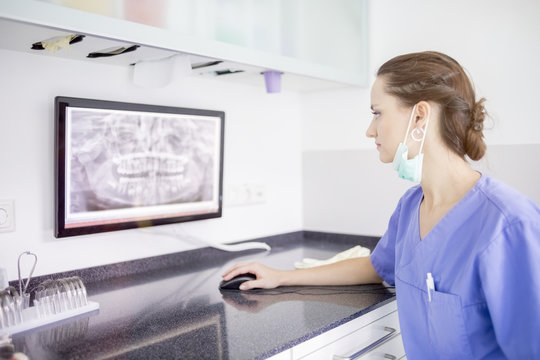 Female dentist examining x-ray of teeth on screen