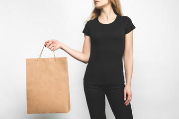 Fototapeta na wymiar young woman in blank black t-shirt on white with shopping bag