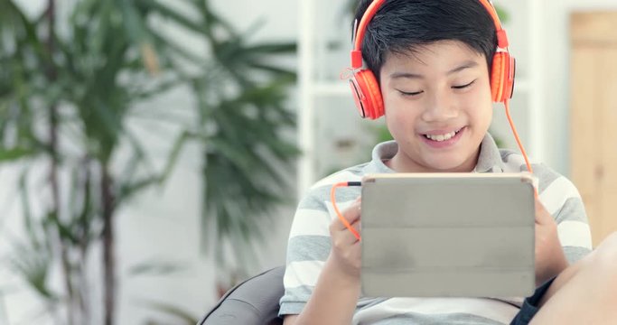 Asian pre teens playing tablet computer with smile face at home.