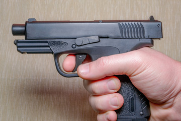 Black gun in the man's hand on light coloured background