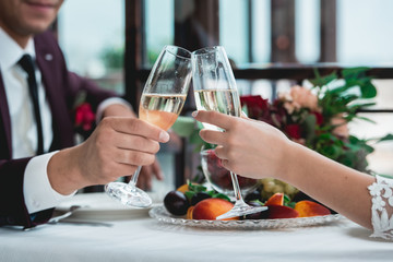 Glasses with champagne drink in bride and groom hands. Happy newlyweds drinking. Loving couple created new family.