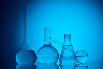 different glass flasks with liquid for chemical test on blue