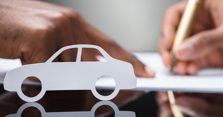 Person's Hand Signing Car Loan Agreement Contract