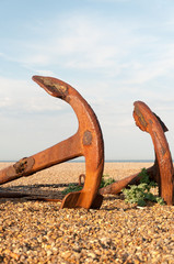 Fototapeta premium Two old, rusted anchors lying on a pebble beach in England
