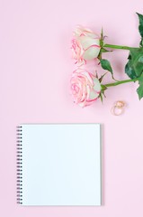 Two pink blooming fresh rose flower with notepad on pink background