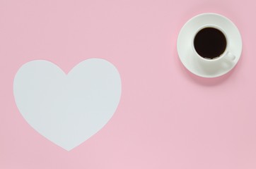 Cup of coffee and paper heart for text on pink background