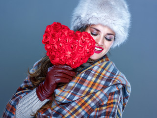 happy young woman isolated on cold blue background holding red heart