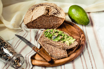 Obraz na płótnie Canvas Avocado toast on gluten-free bread, rustic background. Guacamole with pumpkin seeds.Vegetarian food and Superfood diet concept.