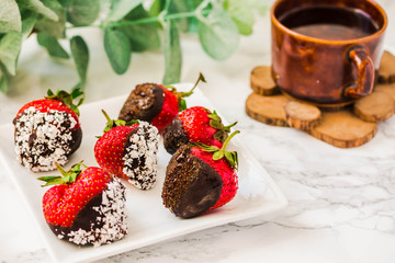 Homemade strawberries dipped in dark chocolate and coconut flakes with a cup of coffee. Breakfast for Valentine's Day or at dessert bar.