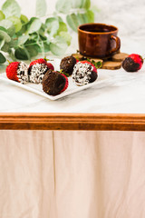 Fresh strawberries dipped in dark chocolate and coconut flakes with a cup of coffee. Breakfast for Valentine's Day. Copy space background.