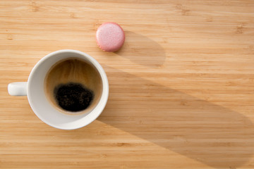 Coffee and macaroons on wooden table in sunlight