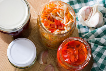 Fermented preserved vegetables in jar on wooden table. 