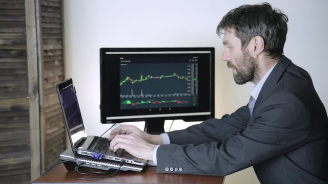 trader watching changes in the currency exchange chart, looking at laptop. Work on a stock exchange.
