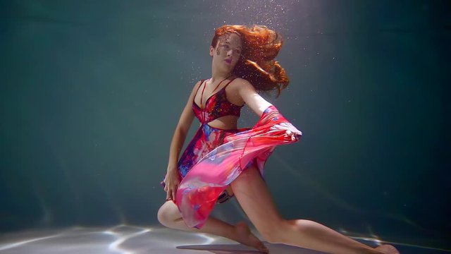 Fantastic woman is freely floating underwater in a crystal water.