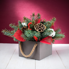 Merry Christmas and Happy New Year! Composition with gray box with fir tree branches and decorative pieces on pink background