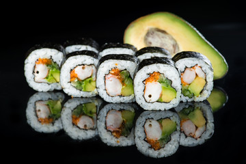 Fresh delicious Japanese sushi with avocado, cucumber, shrimp and caviar on dark background